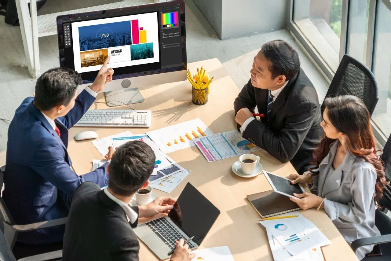 Team reviewing a logo and layout mockup on a monitor