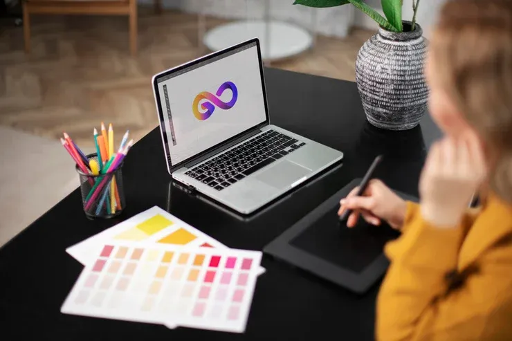 Logo designer working on a tablet connected to a laptop