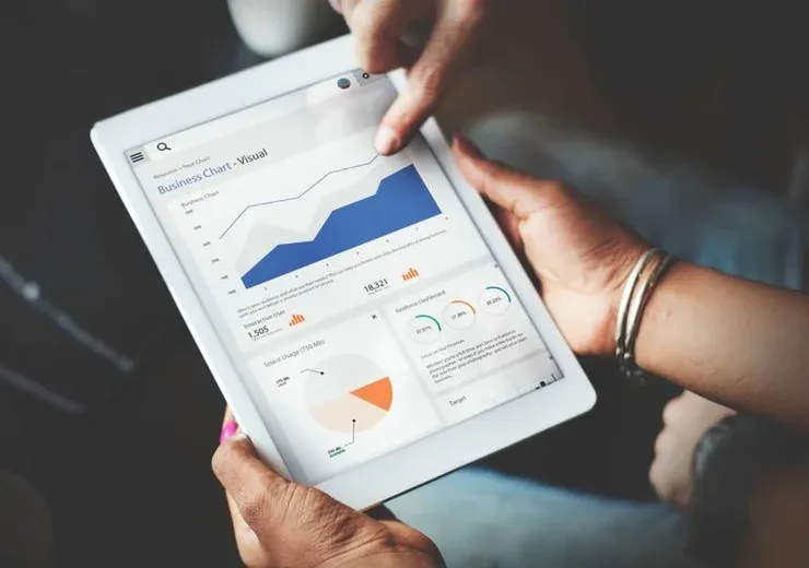 Hands using a tablet that shows business statistics