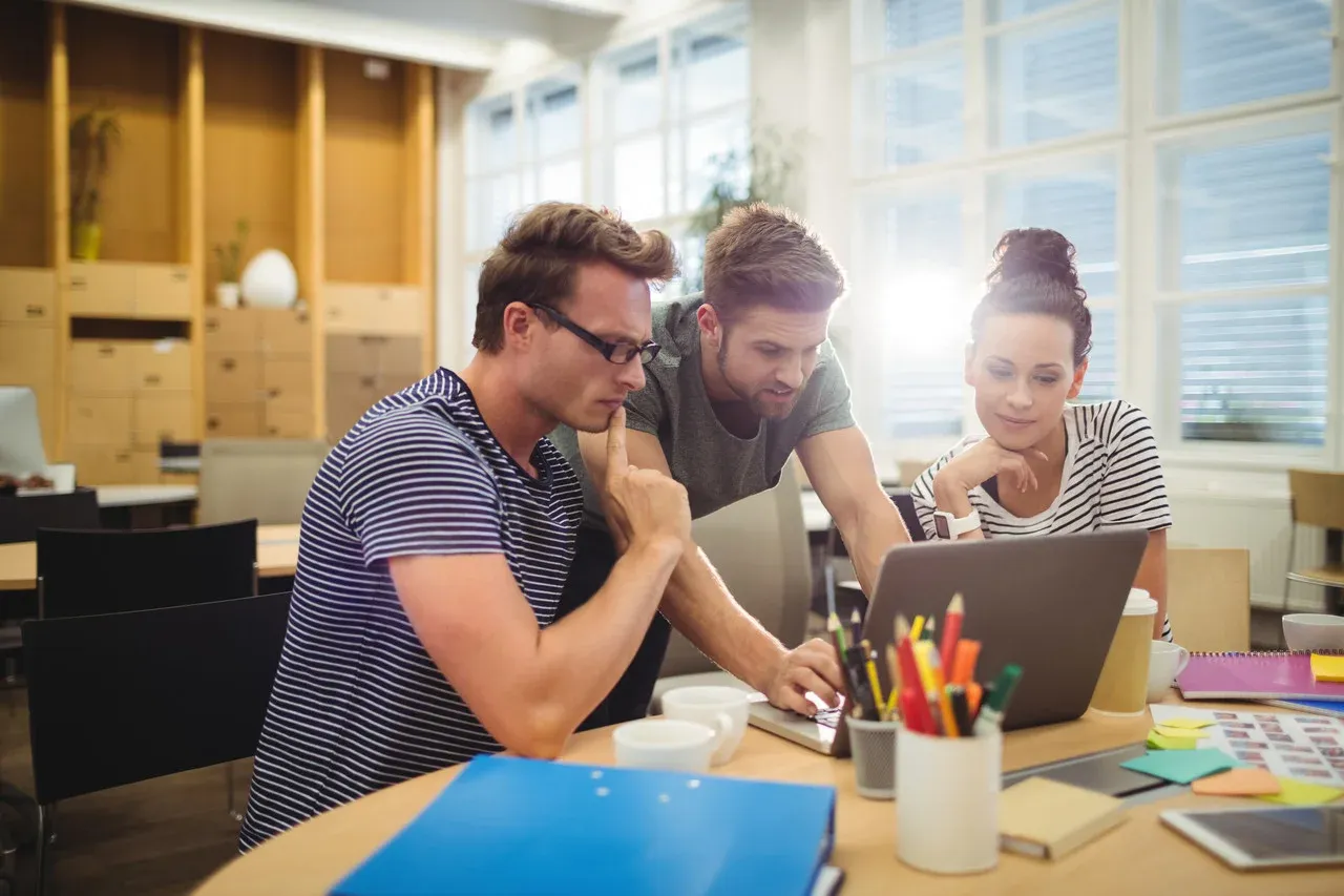 Graphic designers discussing work on a laptop at their desk