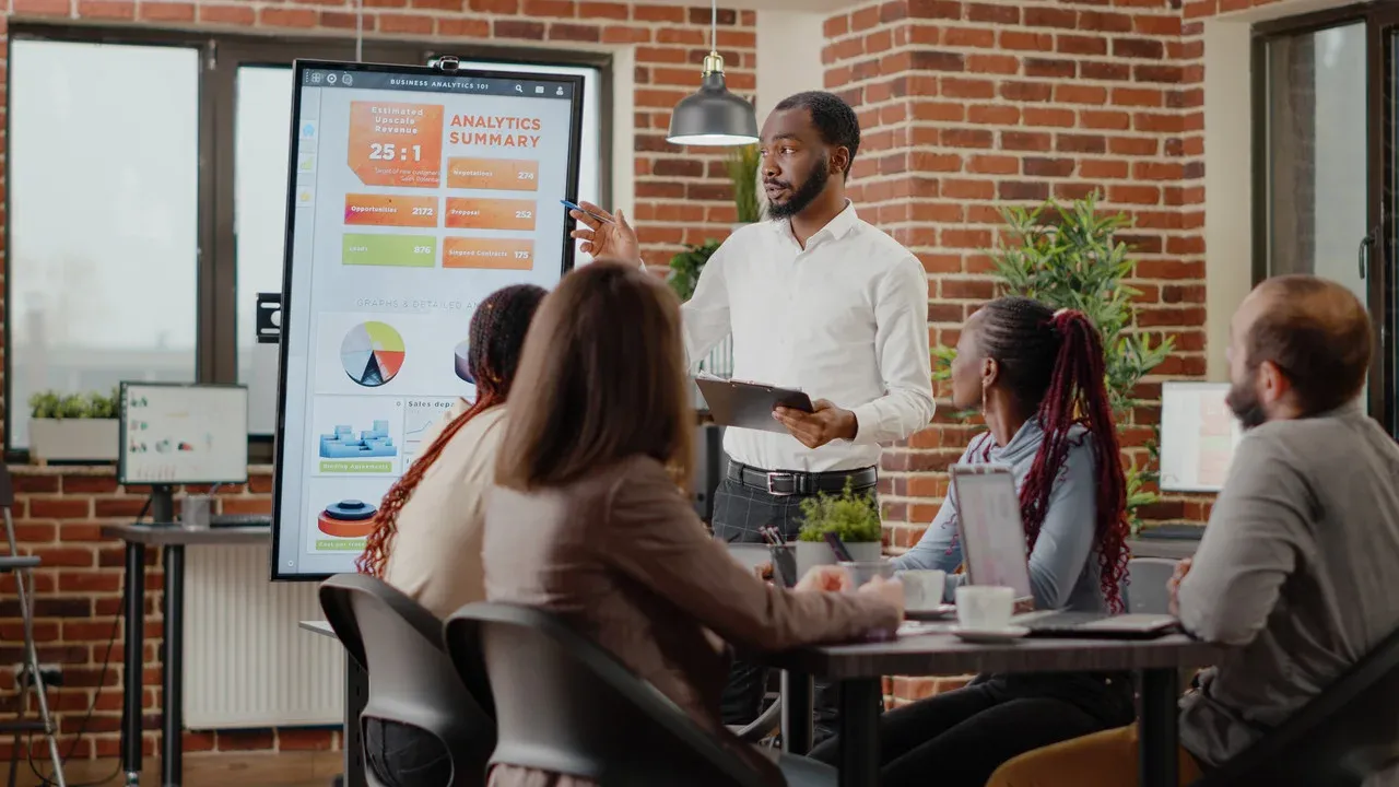 Presenter walking colleagues through an analytics dashboard on a large screen